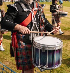 Traditional Scottish drummers and bagpipers performing at an outdoor event in Scotland.