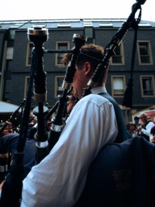 A musician engrossed in playing bagpipes at an outdoor festival.